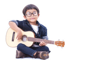 Cute boy playing the ukulele on white background
